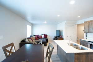 Kitchen with a kitchen island with sink, sink, and light wood-type flooring