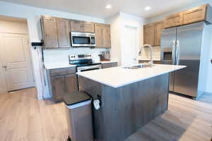 Kitchen featuring sink, a center island with sink, light hardwood / wood-style floors, and appliances with stainless steel finishes