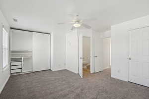 Unfurnished bedroom featuring connected bathroom, carpet floors, and ceiling fan