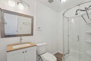 Bathroom with vanity, toilet, a shower with shower door, and hardwood / wood-style floors