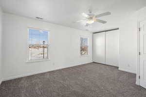 Unfurnished bedroom featuring carpet floors, ceiling fan, and a closet