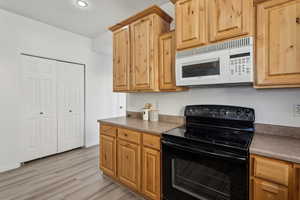 Kitchen with black electric range and light hardwood / wood-style flooring