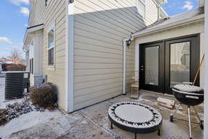 View of exterior entry with central AC and a patio