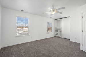 Unfurnished bedroom with ceiling fan and dark colored carpet