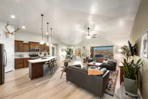 Living room with ceiling fan, sink, high vaulted ceiling, and light hardwood / wood-style flooring