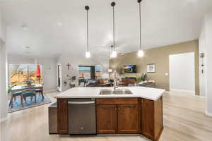 Kitchen featuring dishwasher, pendant lighting, a kitchen island with sink, and sink