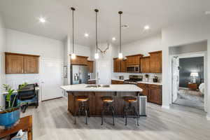 Kitchen featuring an island with sink, sink, a kitchen breakfast bar, hanging light fixtures, and stainless steel appliances