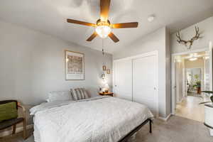 Bedroom with vaulted ceiling, light colored carpet, a closet, and ceiling fan