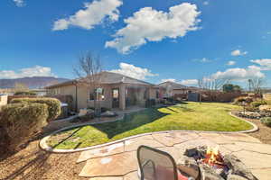 Back of house featuring a mountain view, a yard, a patio area, and a fire pit