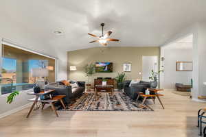 Living room with ceiling fan, vaulted ceiling, and light hardwood / wood-style flooring