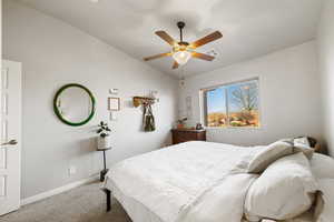 Carpeted bedroom with ceiling fan and lofted ceiling