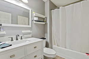 Full bathroom with vanity, toilet, and shower / bath combo with shower curtain