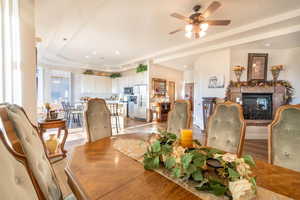 Dining area with a multi sided fireplace, a tray ceiling, ceiling fan, and light hardwood / wood-style flooring