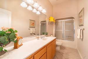 Full bathroom with enclosed tub / shower combo, tile patterned floors, toilet, and vanity