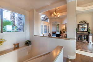 Corridor with dark wood-type flooring, a wealth of natural light, and a notable chandelier