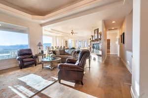 Living room with a mountain view, light hardwood / wood-style flooring, ceiling fan, and a tray ceiling