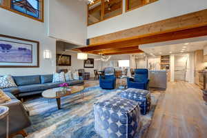 Living room with sink, light wood-type flooring, a high ceiling, a notable chandelier, and beam ceiling