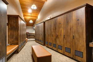 Hallway featuring light colored carpet, vaulted ceiling, and wooden ceiling