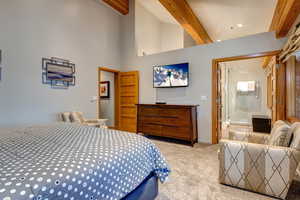 Bedroom featuring light carpet, high vaulted ceiling, and beamed ceiling