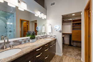 Bathroom featuring a towering ceiling, wood-type flooring, an enclosed shower, and vanity