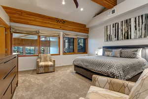 Carpeted bedroom with lofted ceiling with beams and ceiling fan