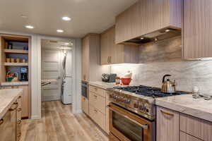 Kitchen featuring custom exhaust hood, light brown cabinets, high end stainless steel range, and white refrigerator