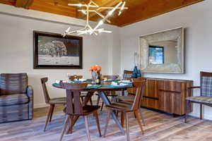 Dining space featuring beamed ceiling, wood ceiling, wood-type flooring, and a notable chandelier