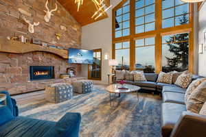 Living room with lofted ceiling, a stone fireplace, wooden ceiling, and hardwood / wood-style flooring