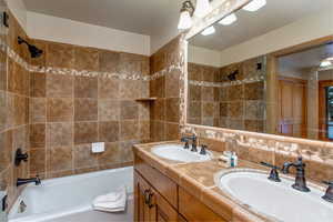 Bathroom featuring tasteful backsplash, tiled shower / bath, and vanity