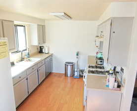 Kitchen featuring gray cabinets, sink, white appliances, and light hardwood / wood-style flooring