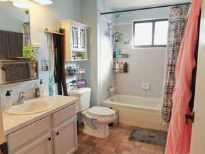 Full bathroom featuring vanity, shower / bathtub combination with curtain, and toilet