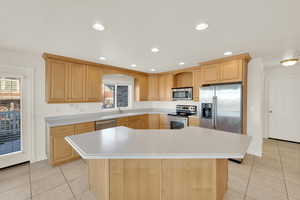 Kitchen with a center island, appliances with stainless steel finishes, light brown cabinetry, and sink