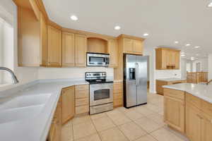 Kitchen featuring light brown cabinetry, sink, light tile patterned floors, and appliances with stainless steel finishes