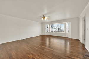 Spare room featuring crown molding, dark hardwood / wood-style floors, and ceiling fan