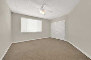 Unfurnished bedroom with carpet, ceiling fan, and a closet