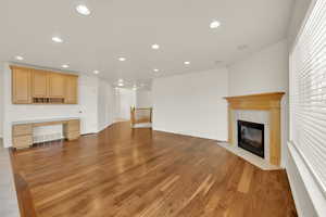 Unfurnished living room with a tiled fireplace, built in desk, and light hardwood / wood-style floors