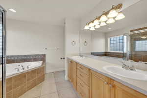 Bathroom featuring tile patterned flooring, vanity, and plus walk in shower