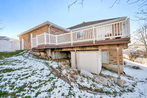 Snow covered rear of property featuring a deck