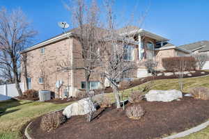 View of side of home with a yard and cooling unit