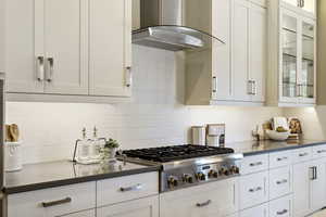 Kitchen with white cabinetry, extractor fan, stainless steel gas cooktop, and decorative backsplash