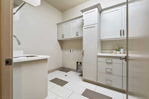 Washroom with cabinets, sink, washer hookup, and light tile patterned floors