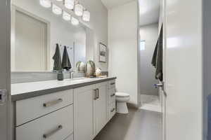 Bathroom with tile patterned floors, vanity, toilet, and a tile shower