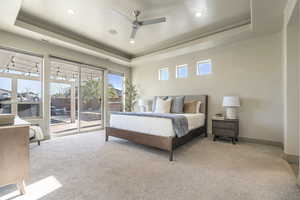 Bedroom featuring light carpet, access to exterior, and a tray ceiling