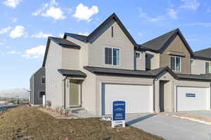 View of front of property featuring a garage, a mountain view, and a front lawn