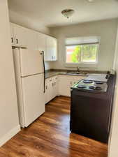 Kitchen featuring sink, white cabinetry, range with electric stovetop, dark hardwood / wood-style flooring, and white fridge