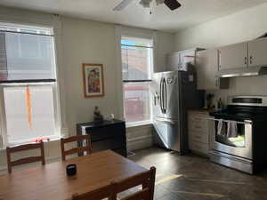 Kitchen featuring appliances with stainless steel finishes, white cabinetry, dark tile patterned flooring, ceiling fan, and a textured ceiling