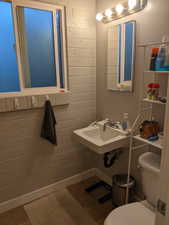 Bathroom with brick wall, toilet, and sink