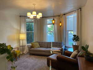 Carpeted living room featuring an inviting chandelier