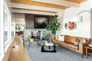 Living room featuring a fireplace, light wood-type flooring, beam ceiling, and wooden ceiling