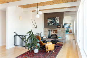 Living room with wood ceiling, a fireplace, beam ceiling, and light wood-type flooring